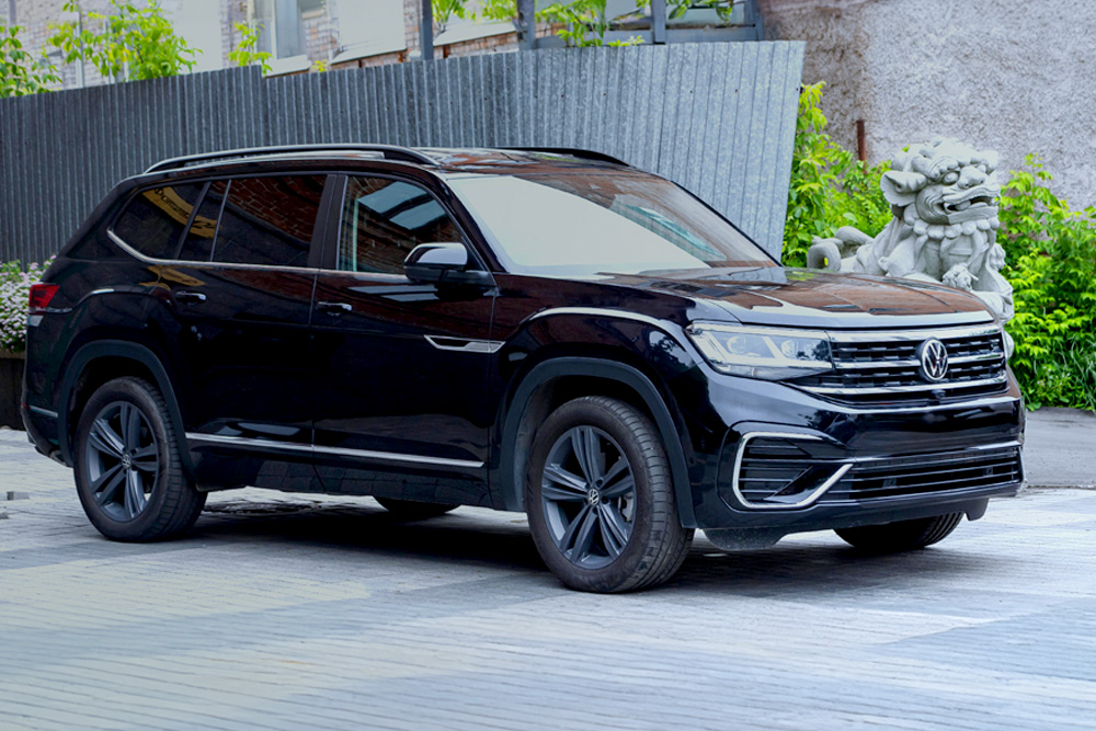 Black Volkswagen SUV parked in front of a fence.